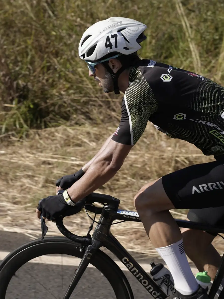 Ciclista em esforço máximo, perfil próximo mostrando o antebraço e a expressão de concentração durante a prova